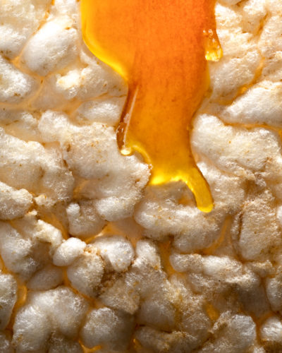 Shooting photo d'un produit, food photography, galette de riz soufflé de la marque Natural Migros, avec du miel qui coule dessus.
