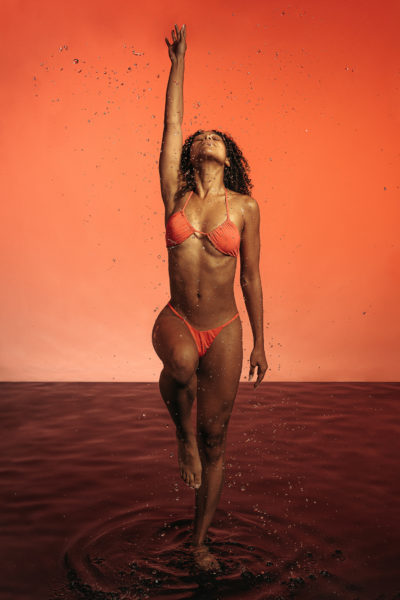 modèle féminin africaine, pose en studio photo pour une marque de maillot de bain suisse, avec de l'eau et des coleurs pour une shooting photo professionnel